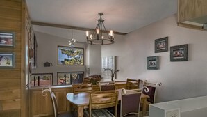 A dining area with wooden furniture, a chandelier, and framed pictures on the walls.