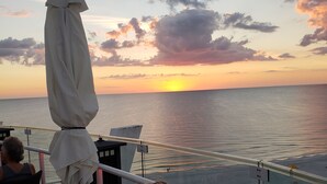 Blick auf den Sonnenuntergang von einem Balkon mit Tisch und Stühlen, mit Meerblick.