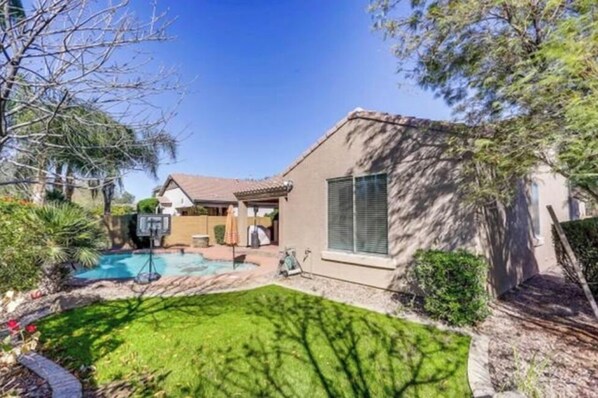 Enjoy a refreshing swim in the backyard pool surrounded by lush trees and a beautifully landscaped lawn.
