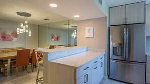 Una cocina moderna con una isla grande, electrodomésticos de acero inoxidable e iluminación contemporánea.