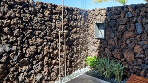 A stone wall, a concrete pathway, and a wooden bench. - 3 Bedroom Home with a Pool at Waikoloa Beach Resort (Waikoloa)