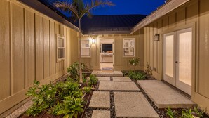 A pathway leading to a house with a covered porch, a small garden, and a door with a window. - 3 Bedroom Home with a Pool at Waikoloa Beach Resort (Waikoloa)