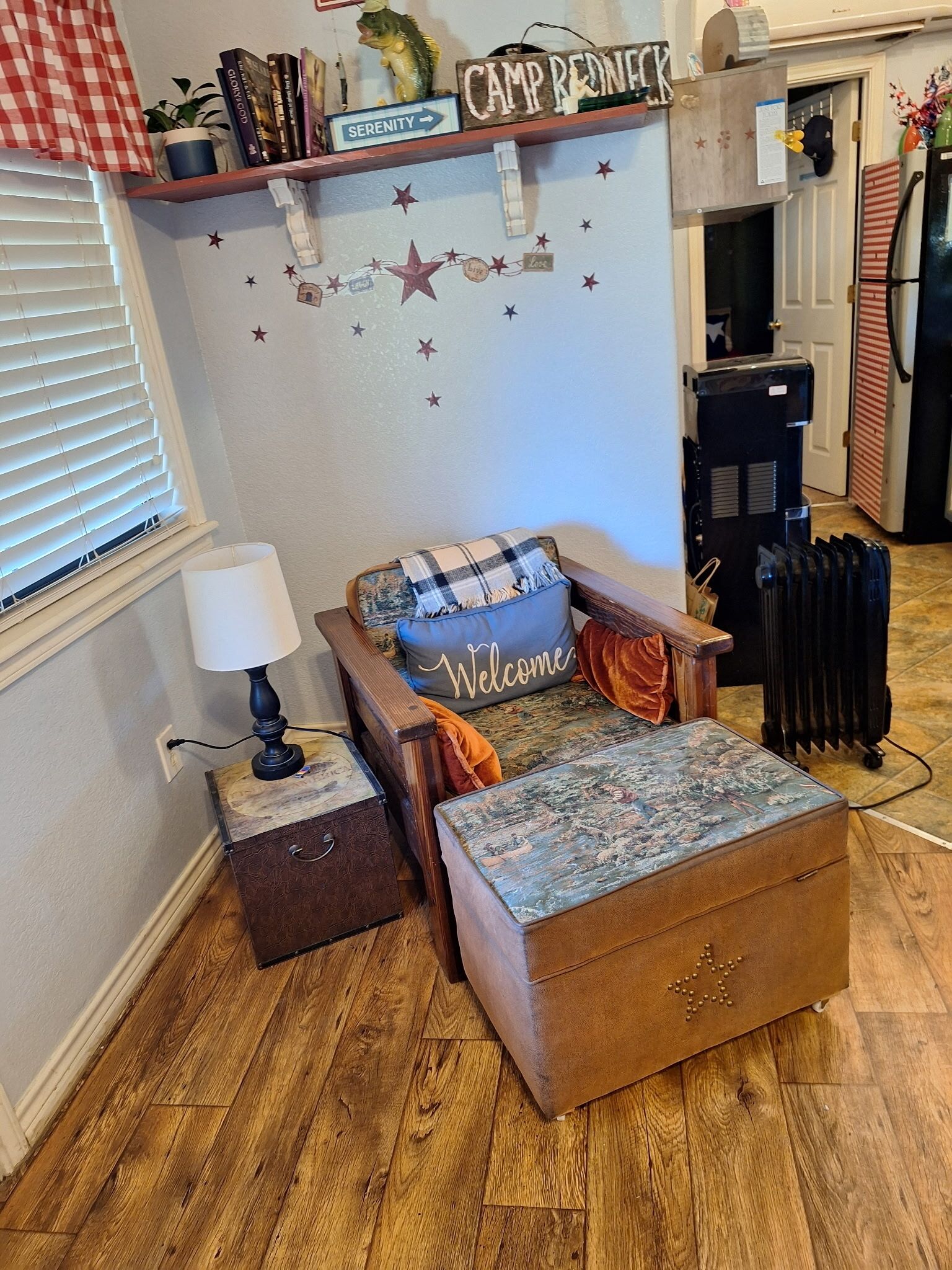 A cozy living room with a sofa, a coffee table, and a fireplace. There is a bookshelf with books and a sign that reads "Camp Redneck."