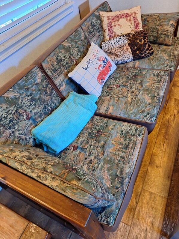 Um sofá modular com estofamento estampado floral, um cobertor azul e almofadas decorativas com diferentes estampas.