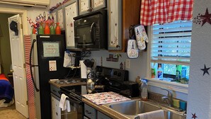 A kitchen with a stove, microwave, refrigerator, and sink. There are cabinets with star decorations and a window with blinds. -  CLEAN, COZY LAKE CABIN COMFORT... (Clifton)