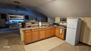 A kitchen with wooden cabinets, a white refrigerator, and a microwave. - Mountain retreat. (Marion)