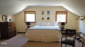 A bedroom with a bed, dresser, two lamps, a chair, and a window with blinds. - Mountain retreat. (Marion)