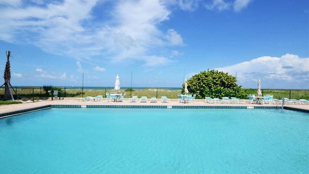 A swimming pool with lounge chairs and a view of the ocean.