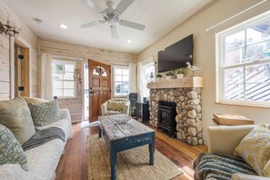 A cozy living room with a stone fireplace, wooden furniture, and a television mounted on the wall. - Perfection! Steps to the Sand w/ AC + Garage! (San Diego)