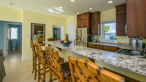 A kitchen with a marble countertop, wooden chairs, and a breakfast bar. - LUXURY PENTHOUSE!! Courtesy SUV Included, PaddleBoards, Bikes, Chairs & More! (Cockburn Town)