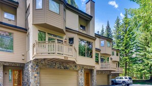 A multi-story residential building with a stone facade, multiple balconies, and garage doors.