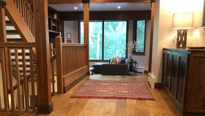 A spacious room with a wooden floor, a staircase, a large window, and a sofa.