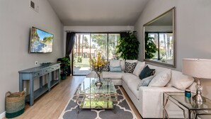 Una sala de estar moderna con una mesa de centro de vidrio, un sofá y un televisor montado en la pared.