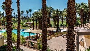 Un resort con piscina, palmeras y zonas de estar al aire libre.