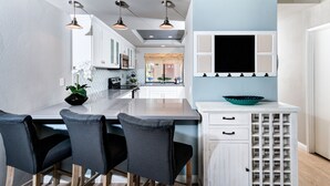 Una cocina moderna con una isla central, luces colgantes y una estantería para vinos.