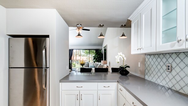 Una cocina moderna con gabinetes blancos, electrodomésticos de acero inoxidable y un salpicadero con diseño.