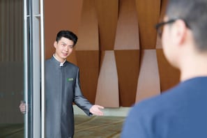 A man in a traditional suit standing in a doorway, gesturing towards someone outside. - Holiday Inn Resort Yichun Mingyue Mountain by IHG (Yichun)
