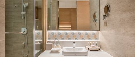 Un baño moderno con ducha acristalada, un espejo grande y un lavamanos de mármol.