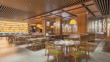 Um restaurante espaçoso com mobiliário de madeira e design moderno no teto.