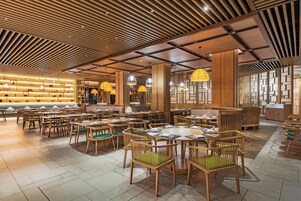 Un restaurante espacioso con muebles de madera y un diseño de techo moderno.