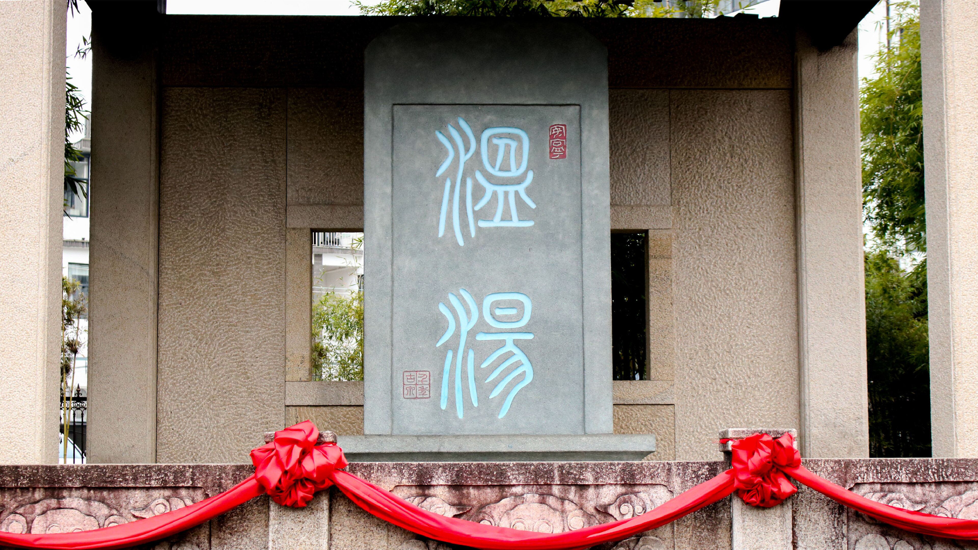 A stone monument with carved Chinese characters and a red ribbon.