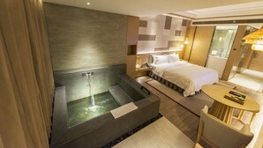 A modern hotel room with a large bathtub, a bed, a small table, and a shower area. - Holiday Inn Resort Yichun Mingyue Mountain by IHG (Yichun)