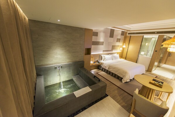Une chambre d’hôtel moderne dotée d’une grande baignoire, d’un lit, d’une petite table et d’un espace douche.