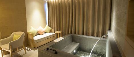 A modern bathroom with a bathtub, a sofa, and a chair.