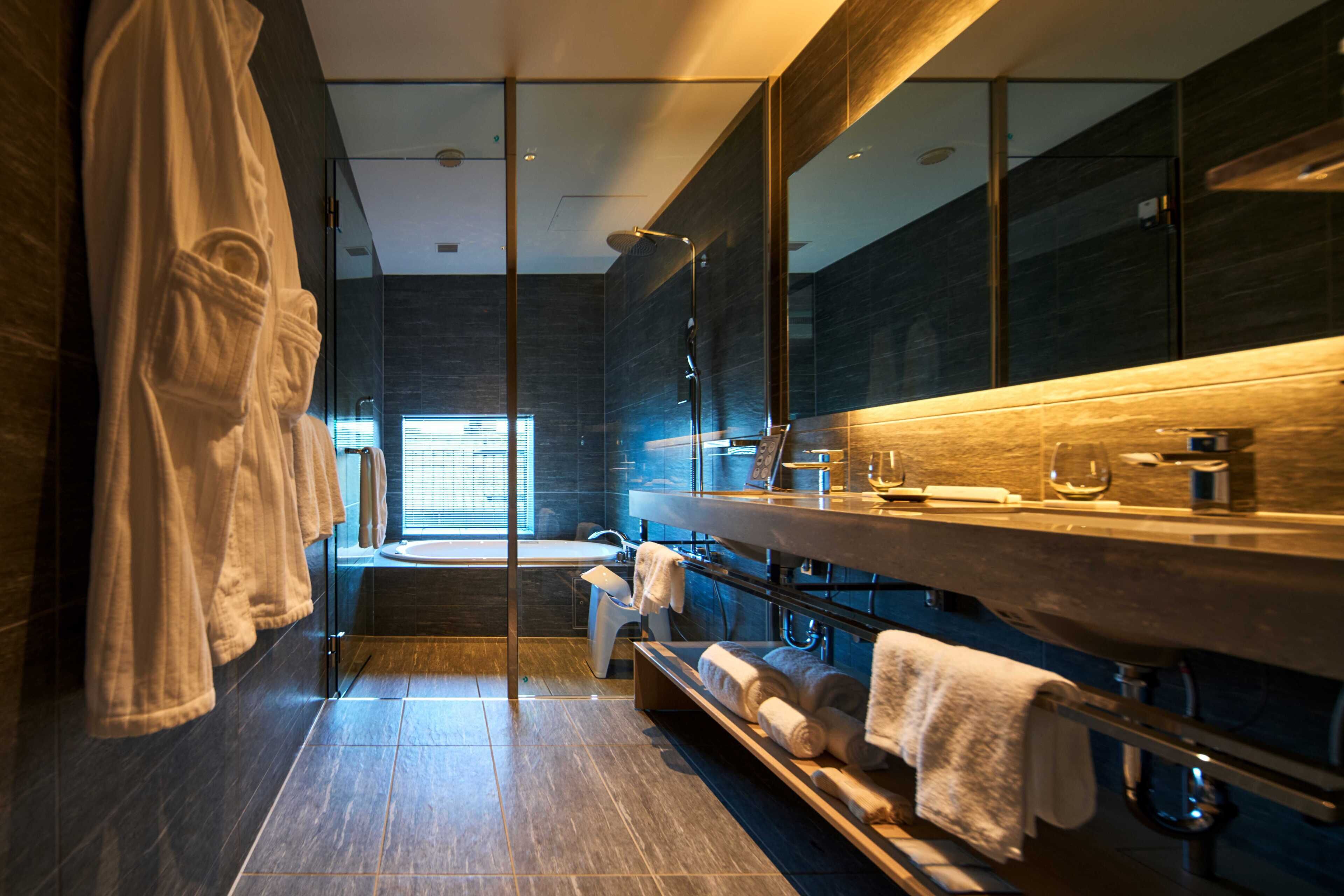 A modern bathroom with a glass shower enclosure, a wooden vanity, and a large mirror.