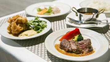 A table with four plates of food, including a steak, vegetables, and fried items.