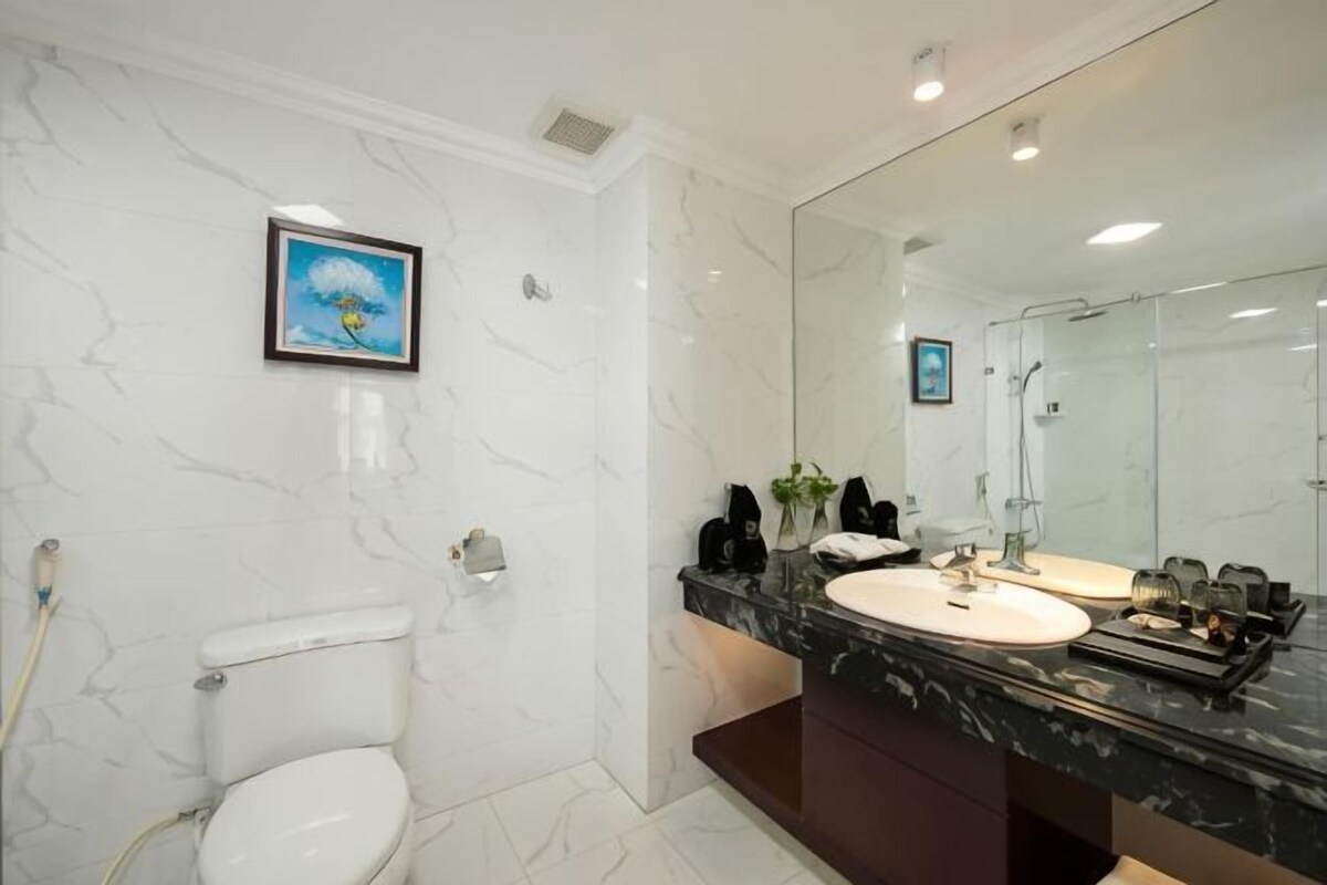 A bathroom with a toilet, two sinks, a large mirror, and a framed picture on the wall.