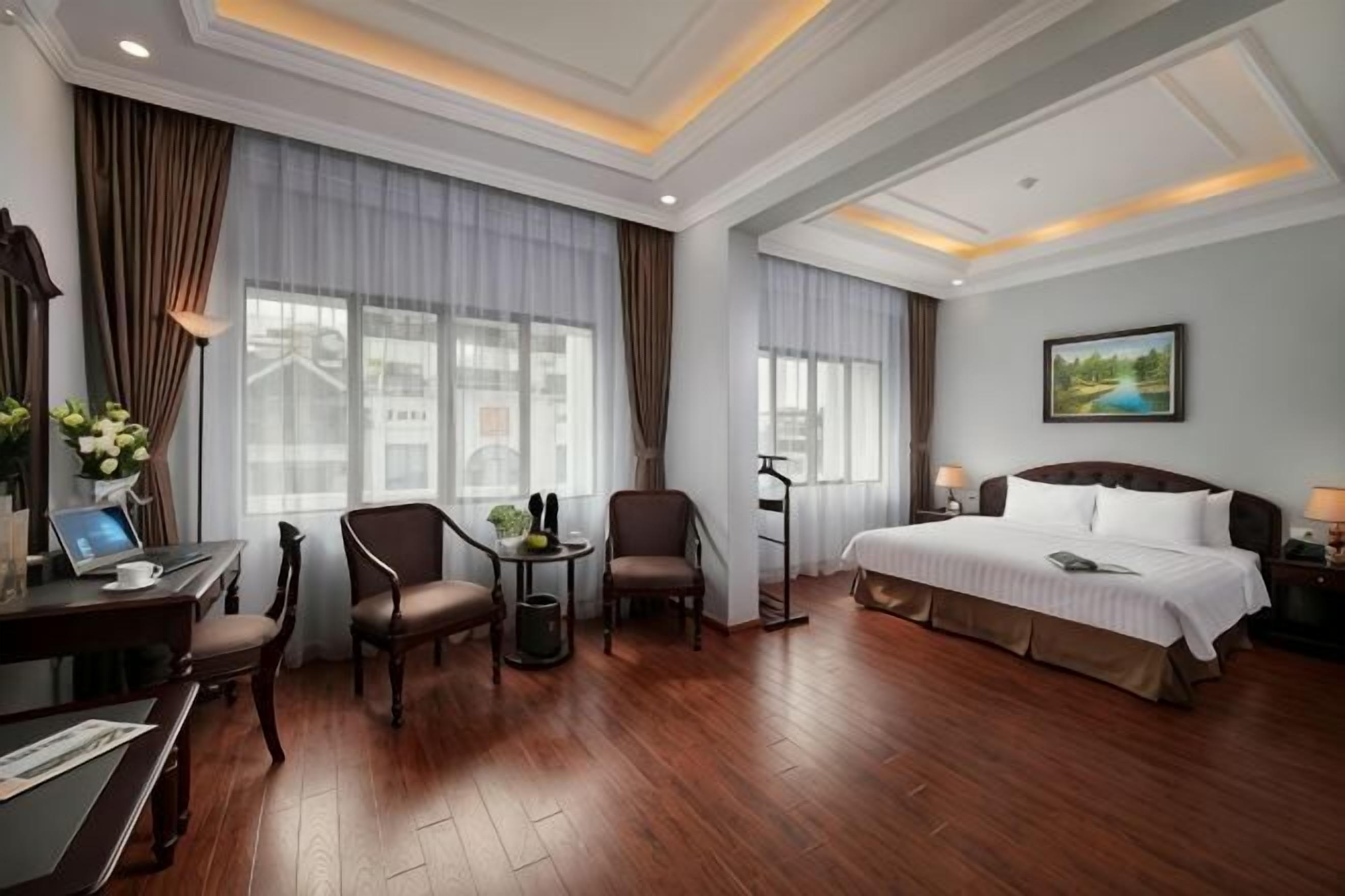 A hotel room with a bed, desk, chairs, and a small table.