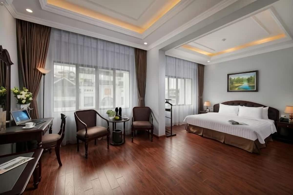 A hotel room with a bed, desk, chairs, and a small table.