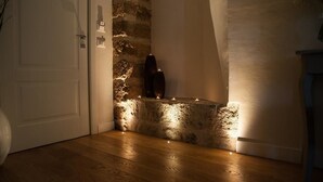 Esquina de una habitación con pared de piedra, suelo de madera y una puerta blanca.