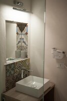 A bathroom with a white sink, a mirror, and a shower.