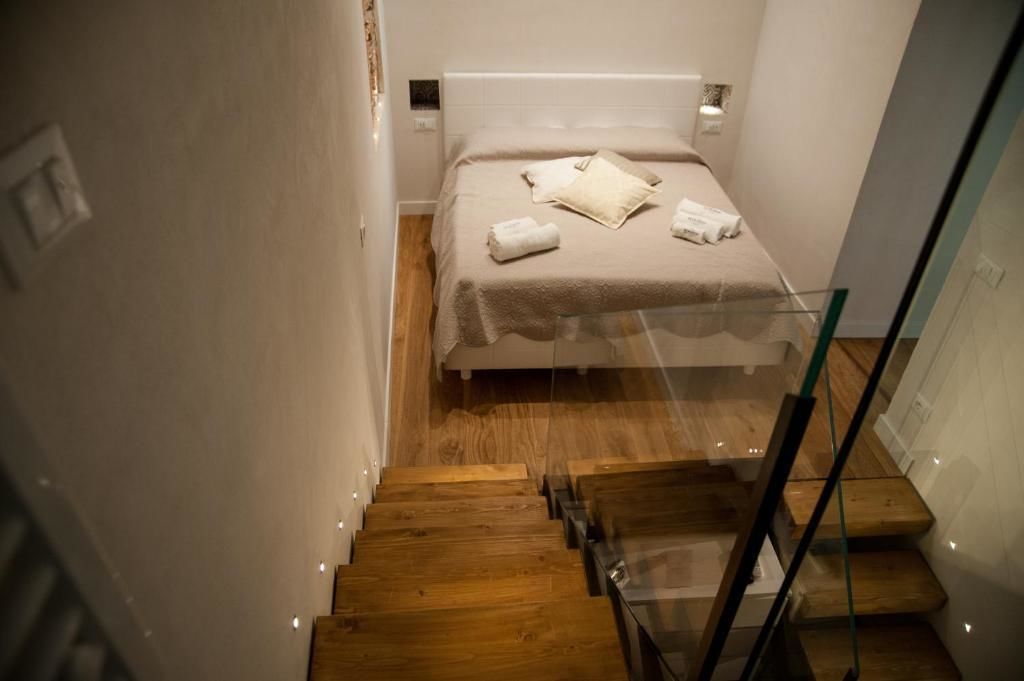 A bedroom with a bed, a glass railing, and a wooden staircase.