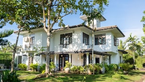 A two-story house with a covered porch, surrounded by lush greenery and a small garden. - Villa Sarakkuwa (Negombo)