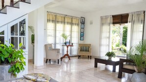 A spacious living room with a sofa, chairs, a coffee table, and potted plants. - Villa Sarakkuwa (Negombo)