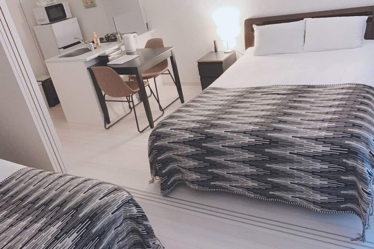 A hotel room with a bed, a desk with a chair, a microwave, and a nightstand.