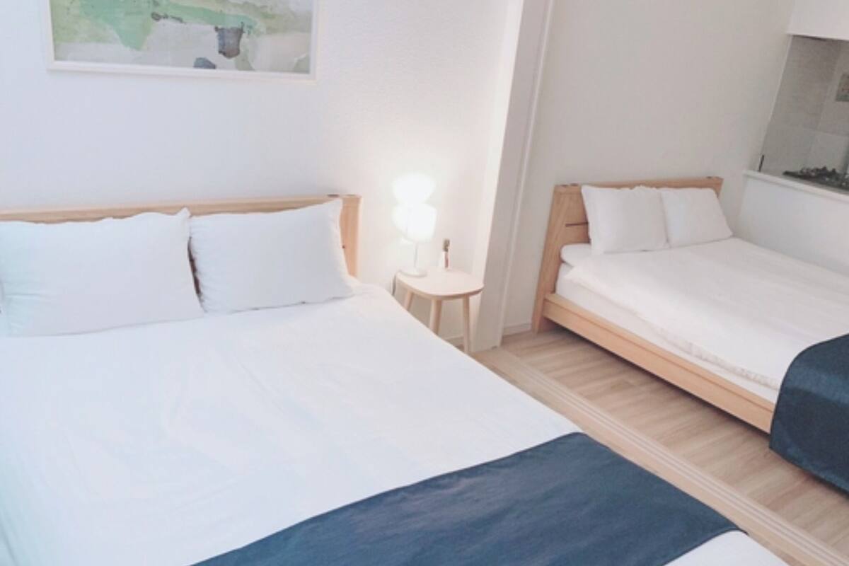 A hotel room with two beds, a small table, and a wall-mounted artwork.