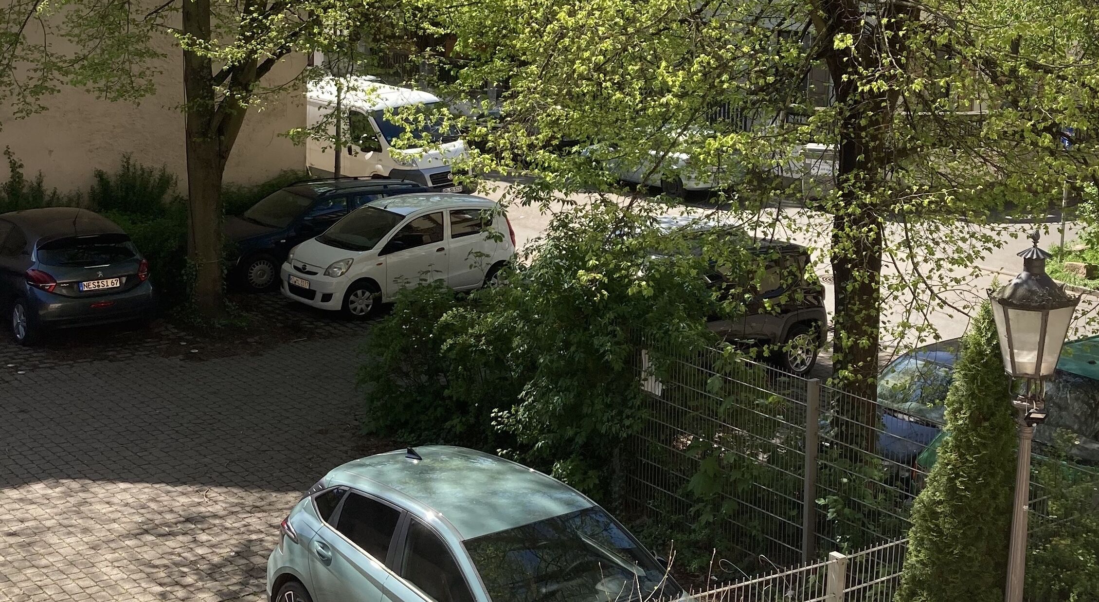 A parking area with several cars, including a white hatchback and a blue sedan.