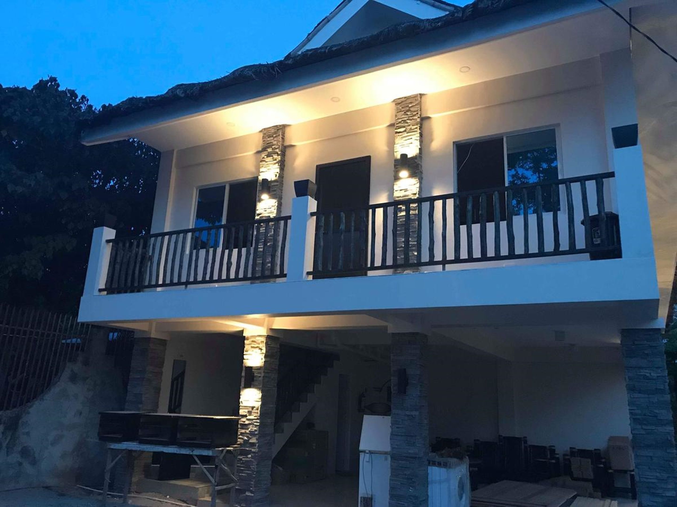 Une maison à deux étages dotée d’un balcon, de piliers en pierre et d’un escalier menant à l’étage supérieur.
