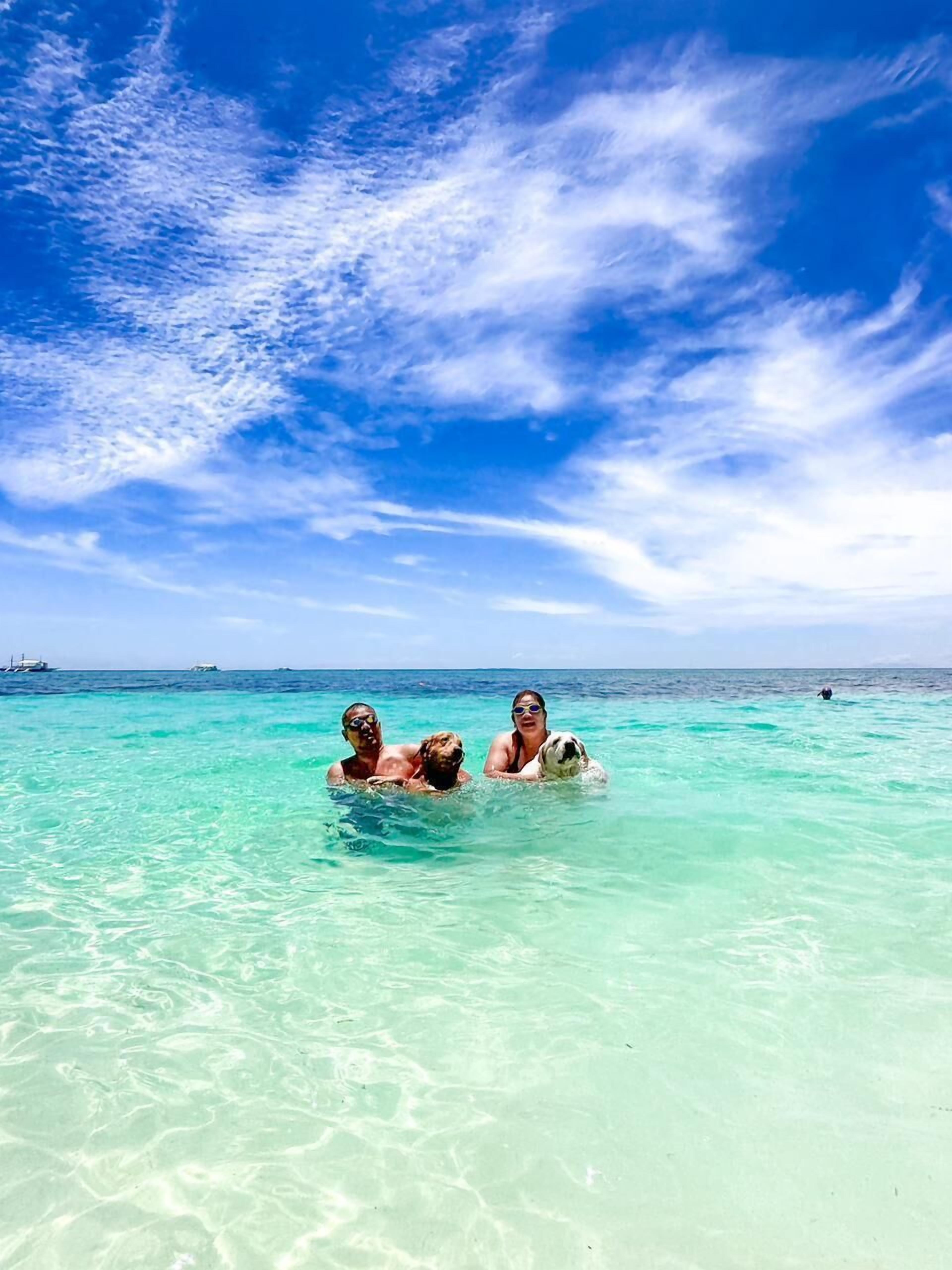 A clear turquoise sea with a few boats in the distance.