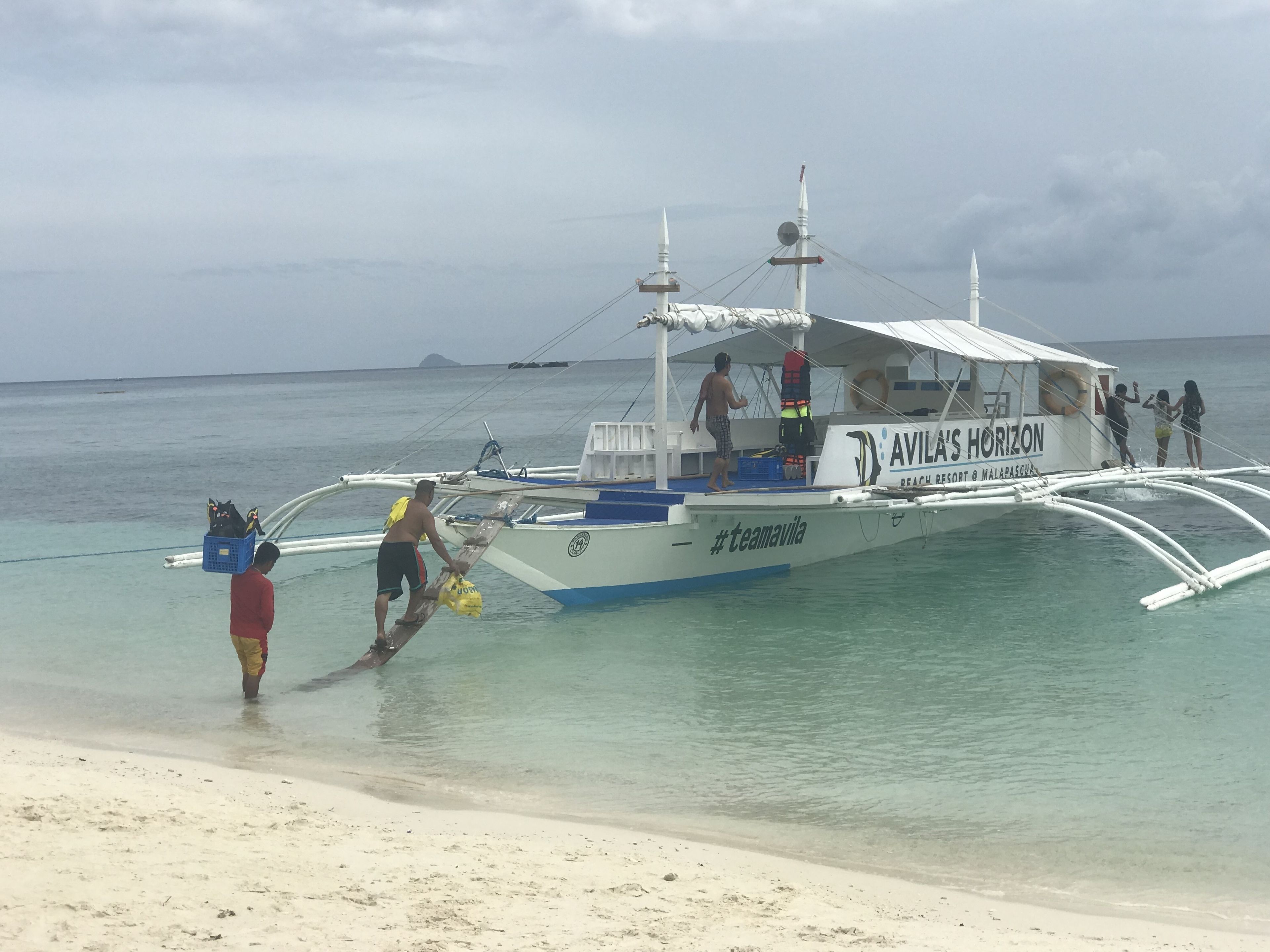 A boat named "AVILA'S HORIZON" docked at a beach.