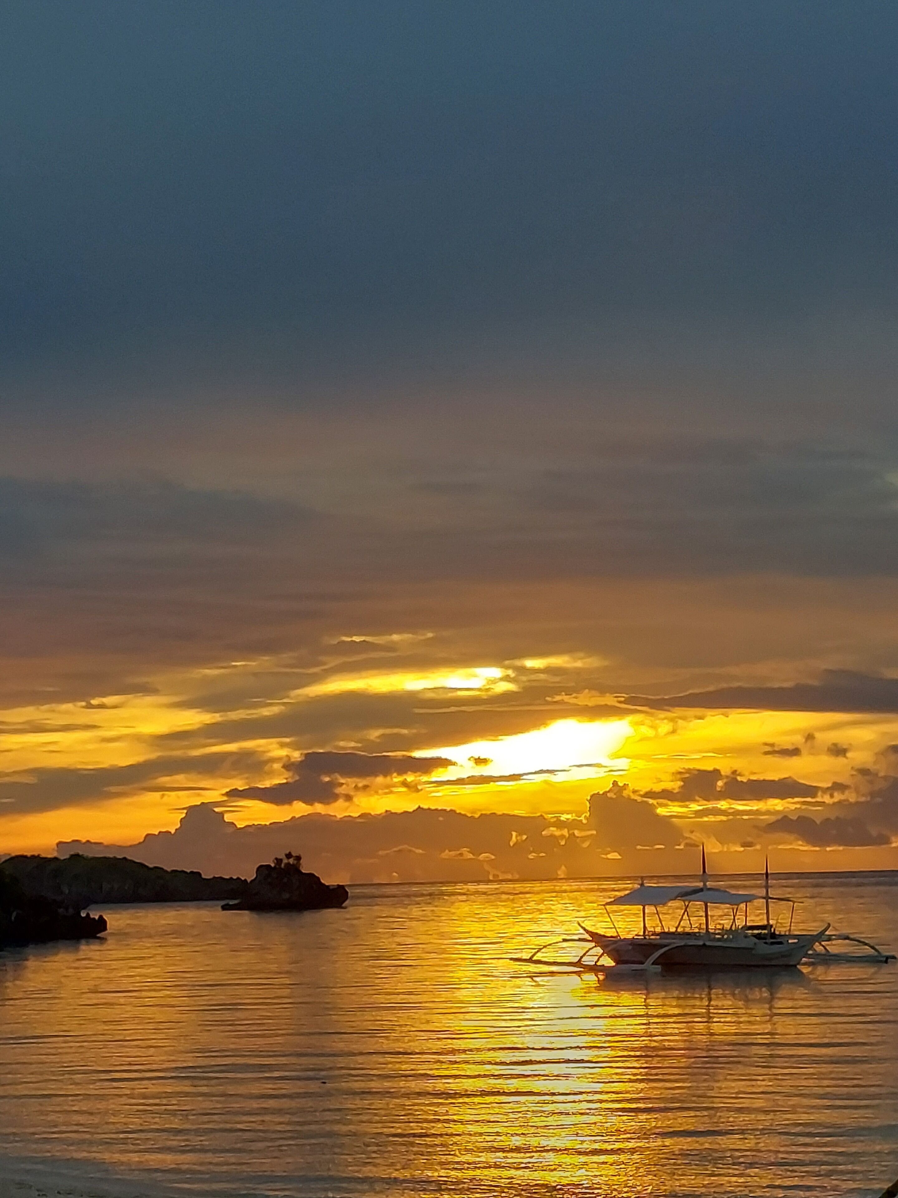 A sunset over a calm body of water with boats.