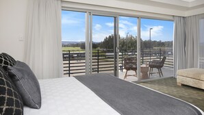 A bedroom with a large bed, a view of a balcony with outdoor furniture, and a sliding glass door leading to a terrace. - Springs  Shoalhaven (Worrigee)