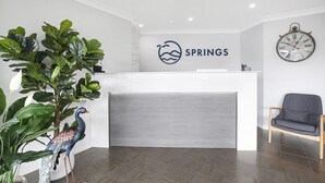 A reception desk with a logo, a clock, and a peacock statue. - Springs  Shoalhaven (Worrigee)