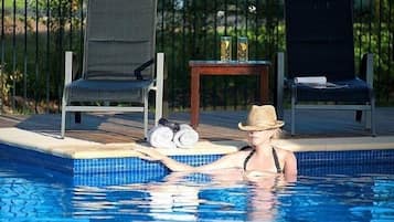 Una piscina con sillones de descanso y una mesa con toallas y botellas.