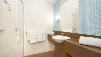 A bathroom with a glass shower enclosure, a sink, and a mirror.