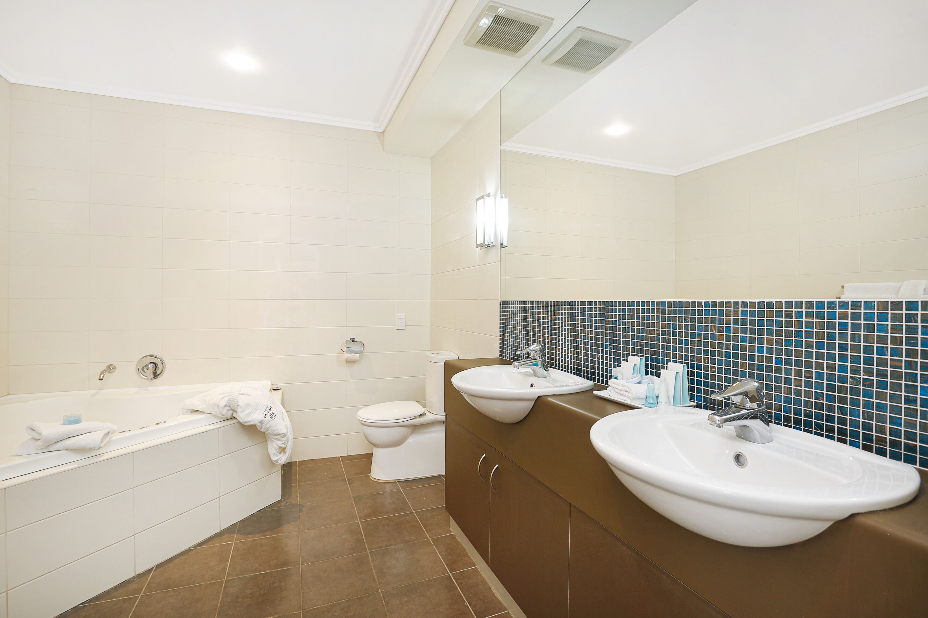 Et moderne badeværelse med badekar, to håndvaske og et toilet.